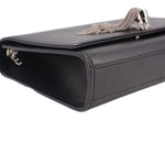 Black leather crossbody bag side view with chain strap hardware and tassel pull