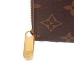 Gold-tone zipper pull with "LOUIS" branding on dark brown monogram wallet