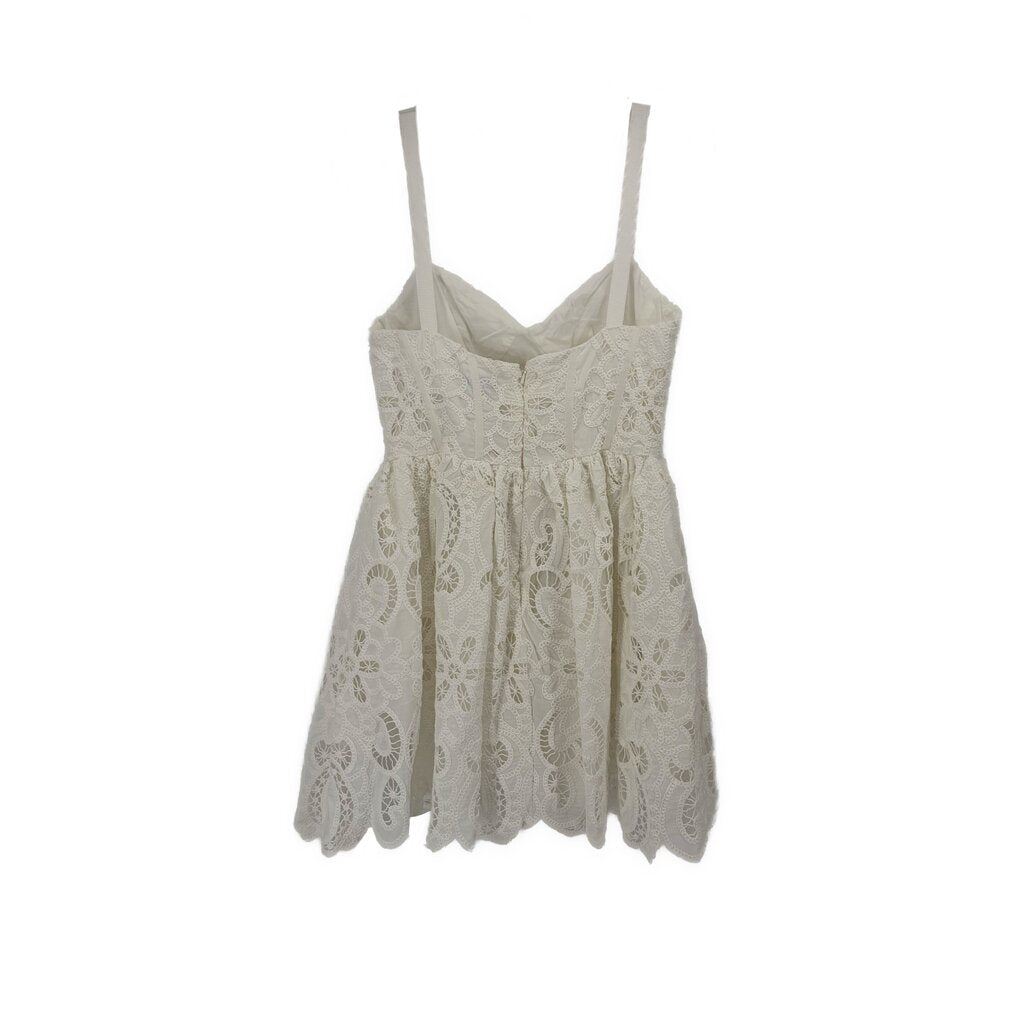 White lace sundress with spaghetti straps, gathered waist, and scalloped skirt hem