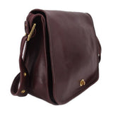 Oxblood leather COACH shoulder bag, side view with gold-tone hardware and strap loops