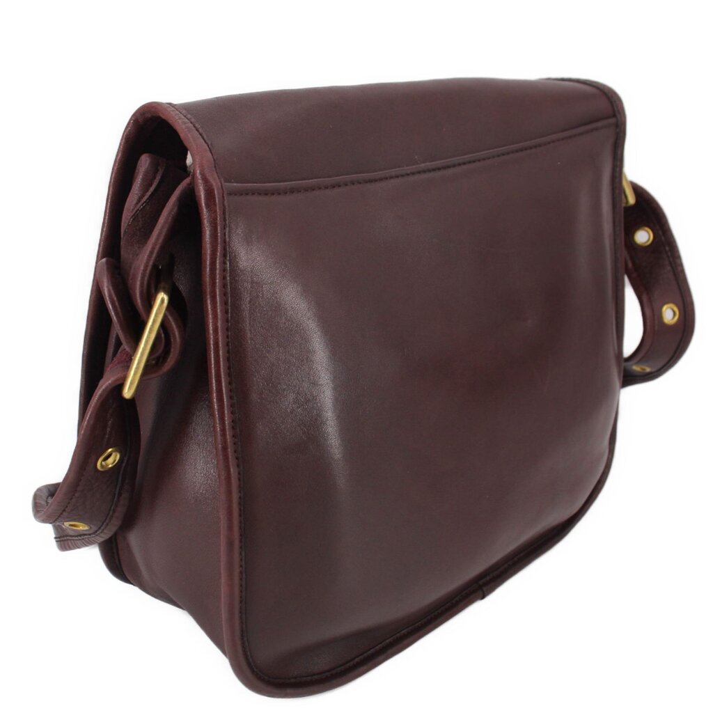 Oxblood leather COACH shoulder bag with flap, strap hardware, and rounded side profile