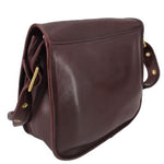 Oxblood leather COACH shoulder bag with flap, strap hardware, and rounded side profile
