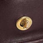 Gold-tone turn-lock clasp on oxblood leather COACH shoulder bag