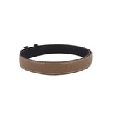 Taupe leather belt with black underside and metal buckle end, stitched border.
