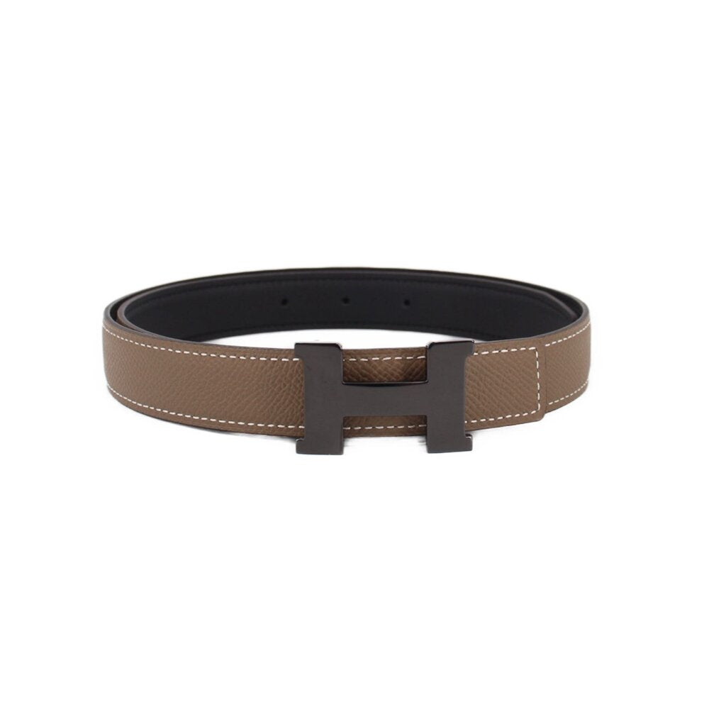 Taupe leather belt with black buckle and stitched edge, adjustable holes.