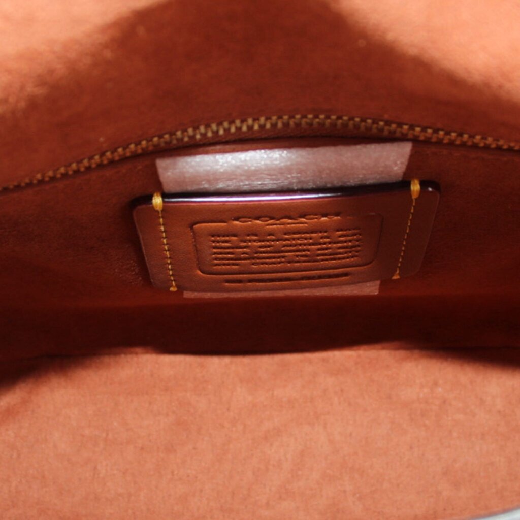Leather crossbody bag interior label patch with gold-toned zipper trim, merlot finish.