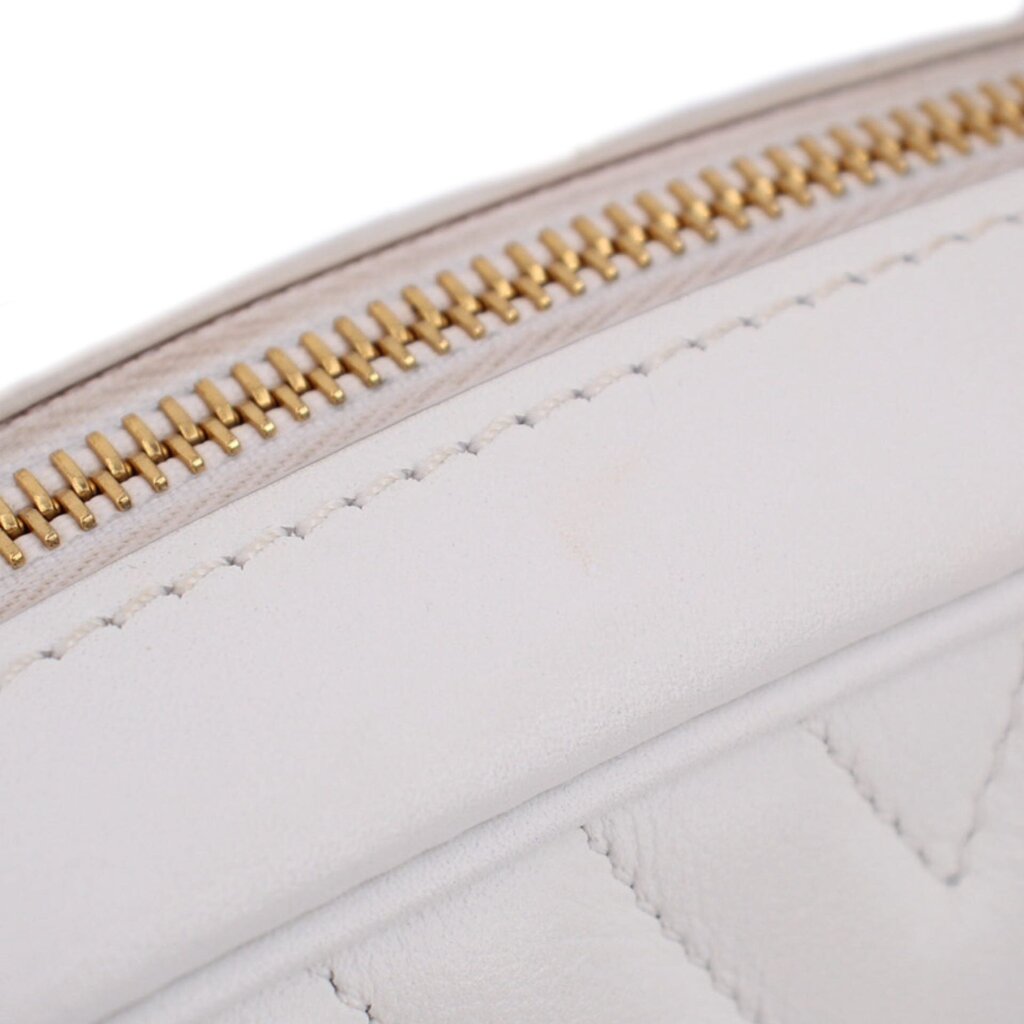 Close-up of gold-tone zipper track on white quilted bag interior