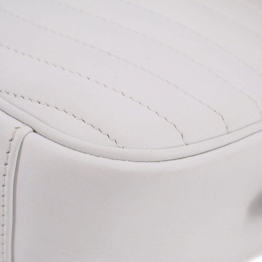 Close-up of white quilted surface with stitched piping along the curved edge