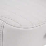 Close-up of white quilted surface with stitched piping along the curved edge