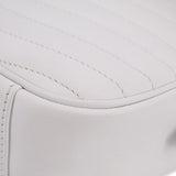 Close-up of white quilted surface with stitched piping along the curved edge