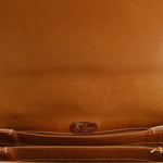 Tan leather crossbody bag with embossed Gucci logo patch and top seam