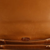 Tan leather crossbody bag with embossed Gucci logo patch and top seam