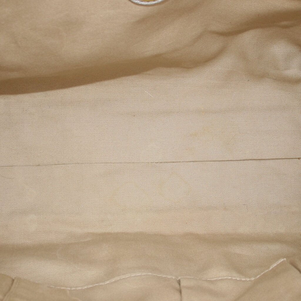 Gold raffia tote bag weave texture close-up with soft fabric lining