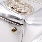 Silver metallic tote bag close-up with gold-tone snap button and embossed logo plate