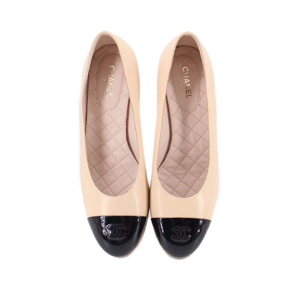 Pair of nude cap-toe heels with glossy black toe caps and quilted insoles