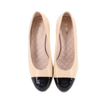 Pair of nude cap-toe heels with glossy black toe caps and quilted insoles