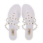 White Valentino rubber Rockstud sandals with gold studs across crossed straps, front view