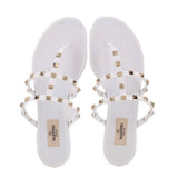 White Valentino rubber Rockstud sandals with gold studs across crossed straps, front view