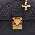Close-up of black monogram flap with gold lock closure and LV logo plate