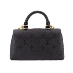 Black monogram mini flap crossbody bag with gold top handles and embossed pattern