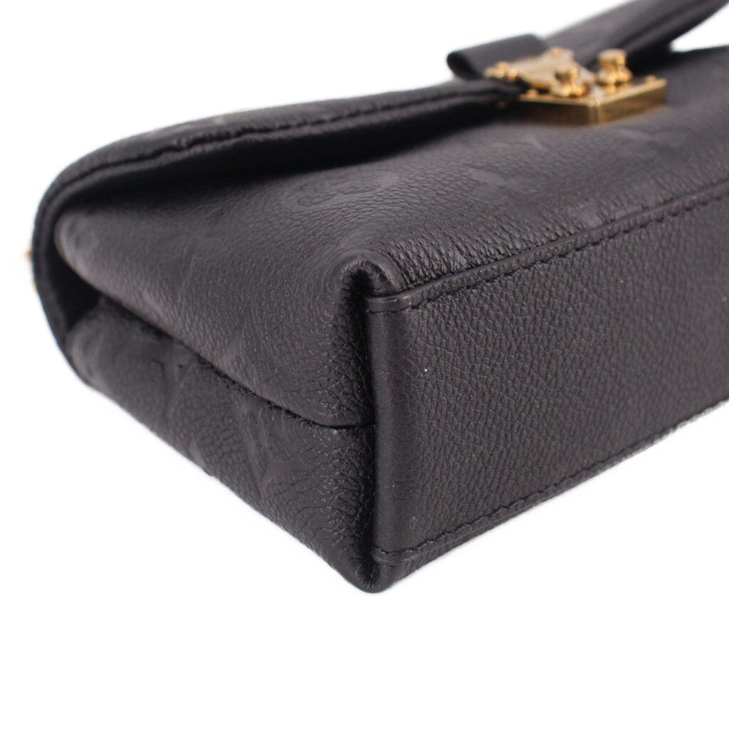 Black leather mini bag corner with smooth flap edge and gold clasp hardware