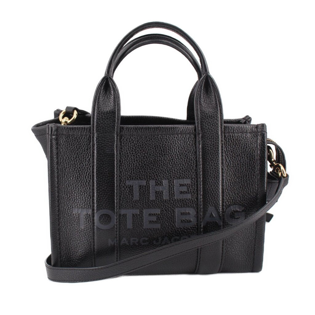 Small black leather tote bag with top handles and crossbody strap, gold-tone hardware