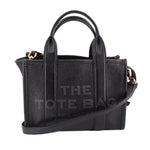 Small black leather tote bag with top handles and crossbody strap, gold-tone hardware