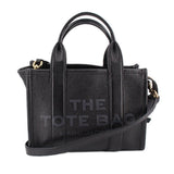 Small black leather tote bag with top handles and crossbody strap, gold-tone hardware