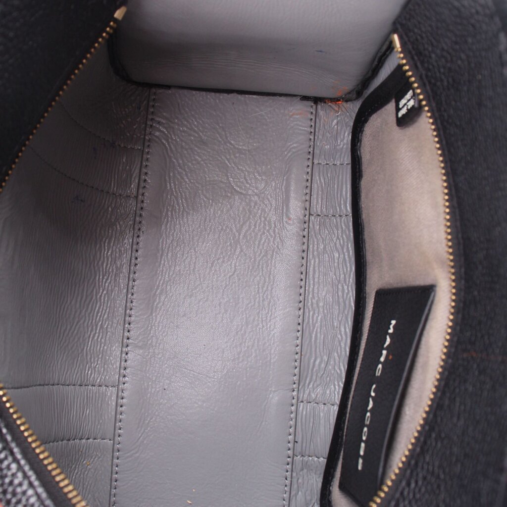 Interior view of black leather tote bag with zip pocket and gold-tone zipper trim