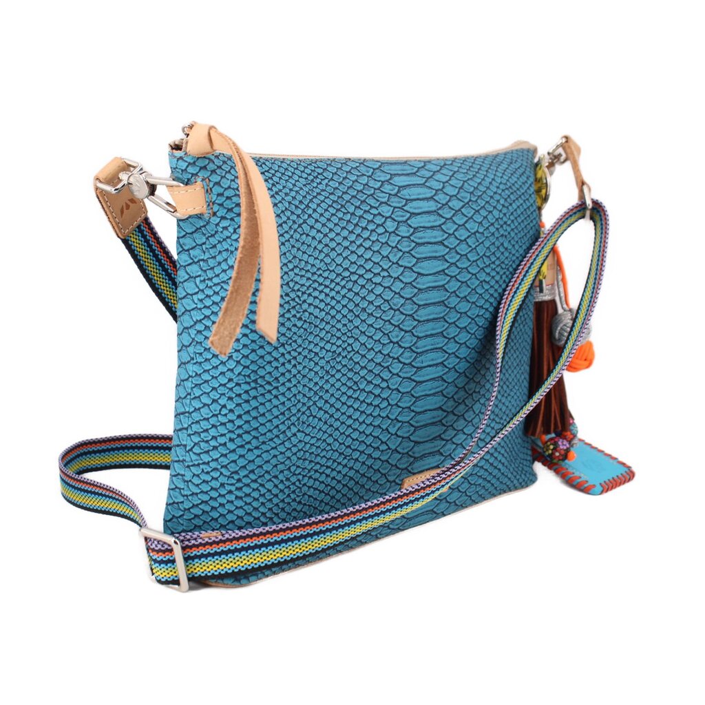 Teal crossbody bag with tan top handle, striped strap, and tassel charm