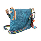 Teal crossbody bag with tan top handle, striped strap, and tassel charm