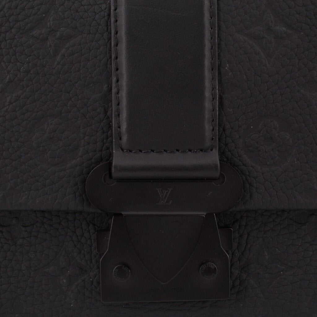 Black leather flap clasp and hardware detail on messenger crossbody bag