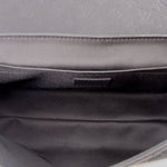 Black fabric interior lining of a black messenger crossbody bag