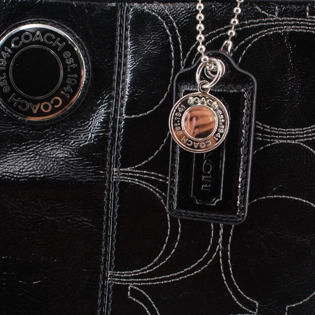 COACH logo on black tote with patterned stitching and hanging charm tag
