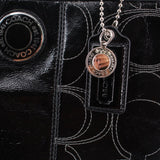 COACH logo on black tote with patterned stitching and hanging charm tag
