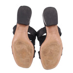 Black slip-on sandals with textured outsole and tan underside view