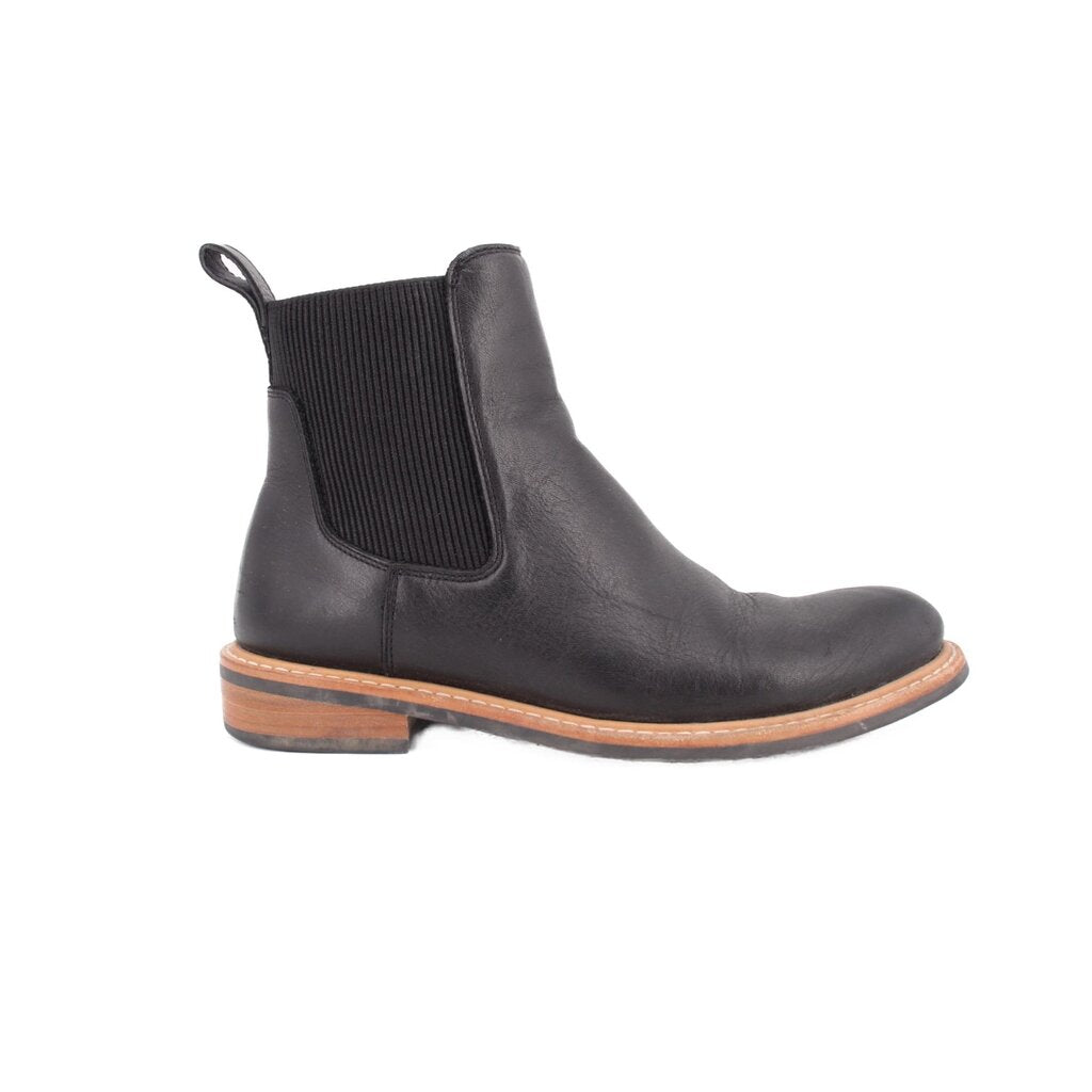 Black leather Chelsea boots with elastic side panels, pull tab, and tan welt; low heel.