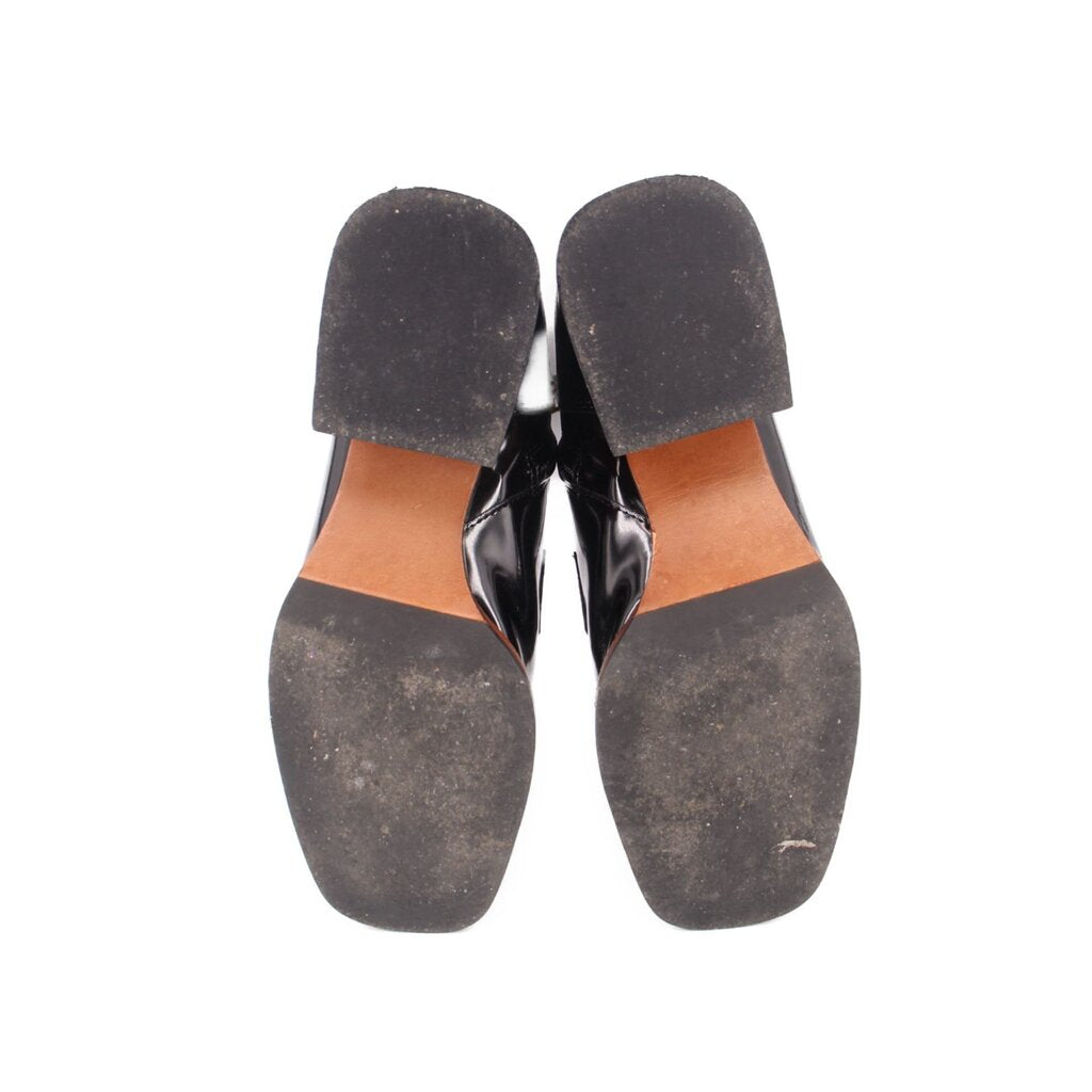 Bottom view of black ankle boots with treaded rubber soles and tan welt