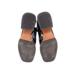 Bottom view of black ankle boots with treaded rubber soles and tan welt
