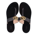 Black sandals with wide strap and gold double-G buckle, flat thong sole