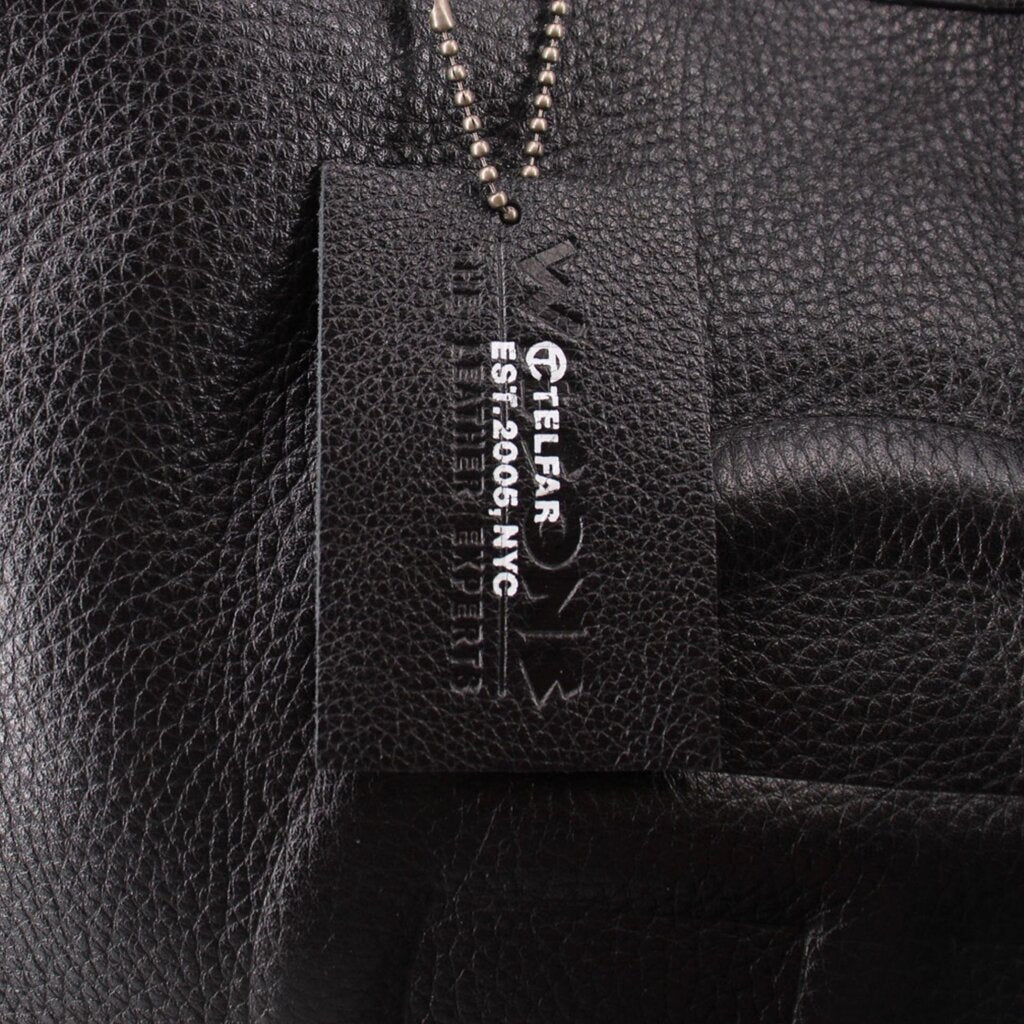Telfar logo brand tag on black leather bag interior, with small product text