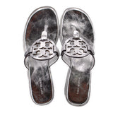 Pair of silver thong sandals with cutout logo strap and cushioned footbeds.