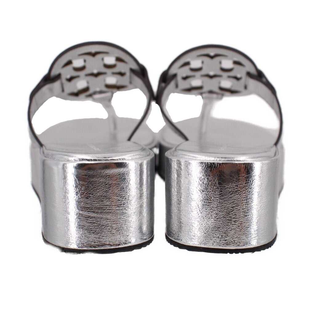 Silver platform wedge sandal heels with openwork logo straps, back view.
