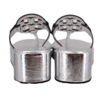 Silver platform wedge sandal heels with openwork logo straps, back view.