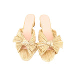 Gold woven heeled slide sandal with bow straps over the toes