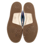 Outsoles of blue New Balance tennis sneakers with textured brown rubber tread