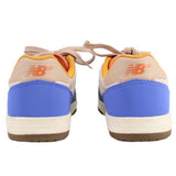 Back view of blue New Balance tennis sneakers with orange logo and tan heel