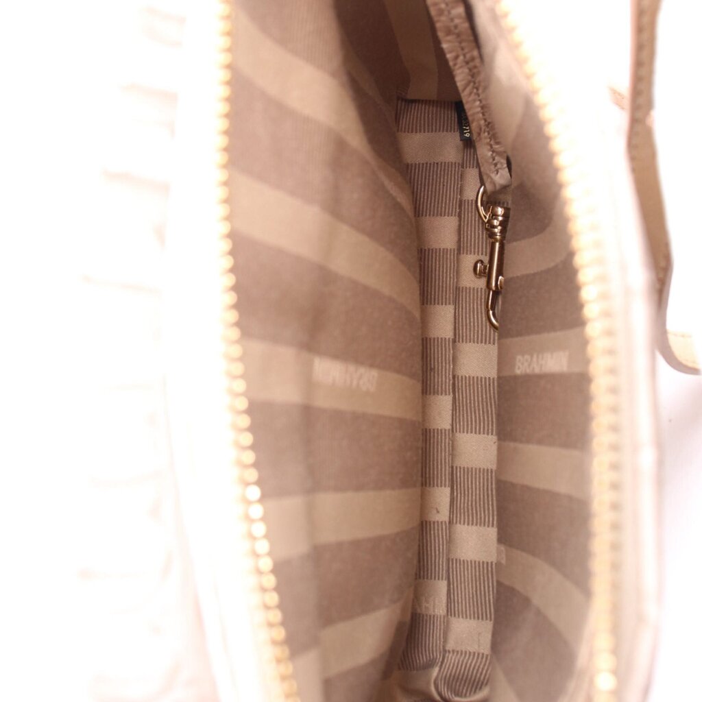 Inside crossbody bag with striped fabric lining and metal zipper pull on pocket.