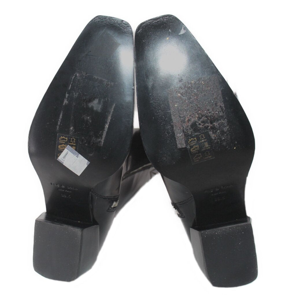 Black tall boot heels and soles underside with visible wear and branded markings