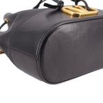 Black mini bucket crossbody bag side close-up with stitched leather trim
